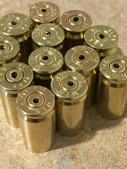 Cluster of polished brass 9mm casing headstamps viewed from above on a speckled countertop