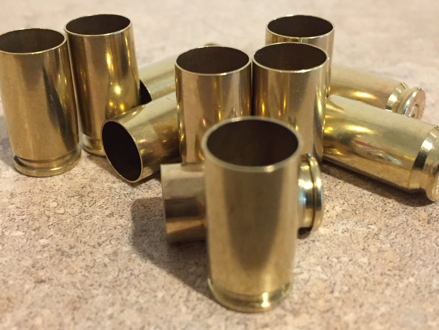 Group of polished brass 9mm empty casings standing open-end up on a tan speckled countertop