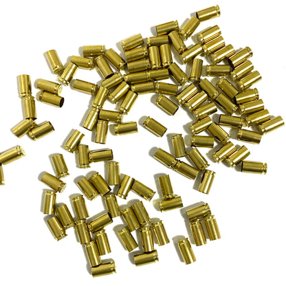 Bulk pile of spent brass 9mm shells scattered across a white background.
