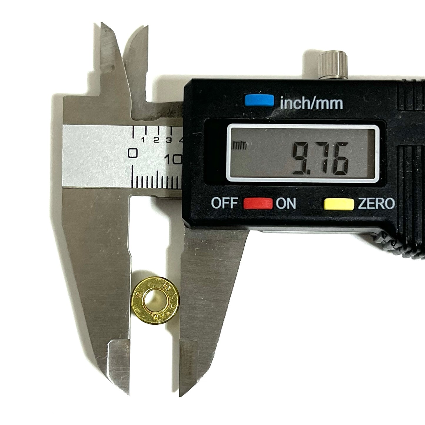 A caliper measures the diameter of a deprimed 9mm bullet slice piece at 9.76 mm, with a hollow center visible.
