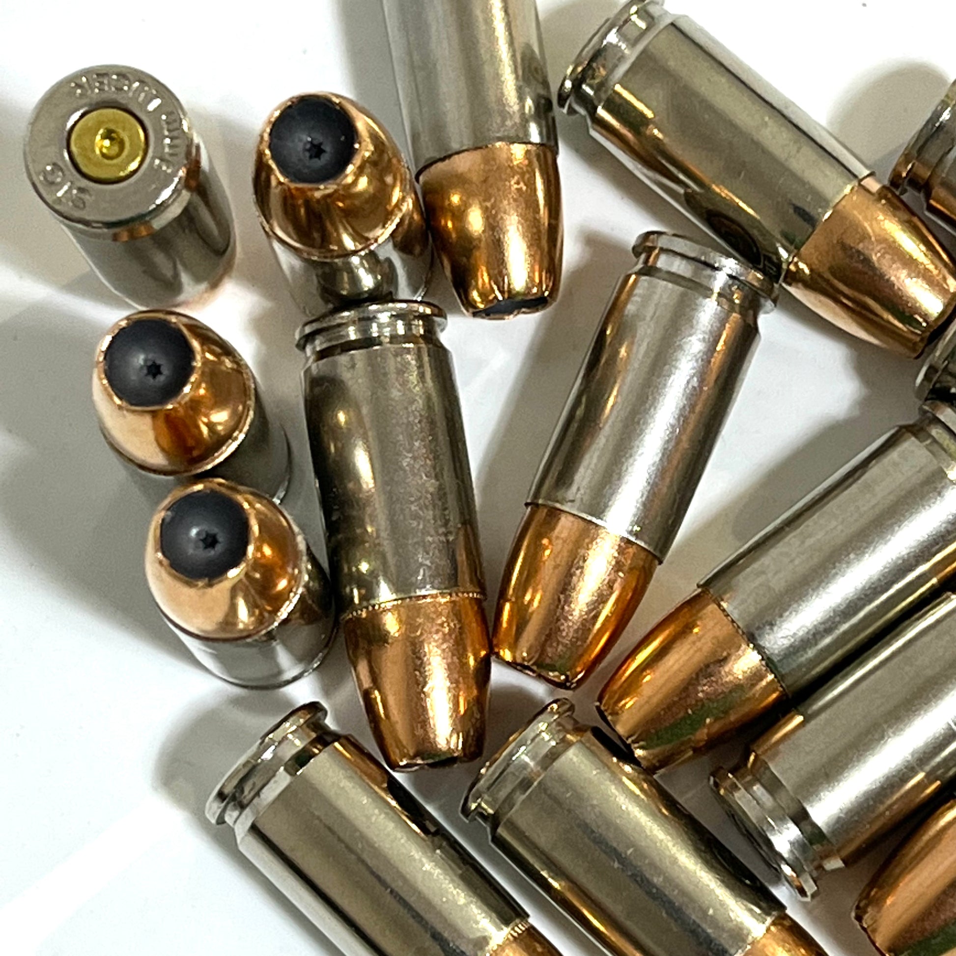 Close-up top-down view of three inert 9MM JHP dummy round bullet tips showing copper jacketed hollow point cavity. Nickel-plated once-fired casings. Safe for display and crafts.
