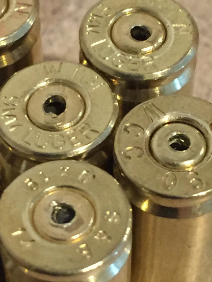 Close-up of polished brass 9mm casing headstamps including Luger and Winchester markings