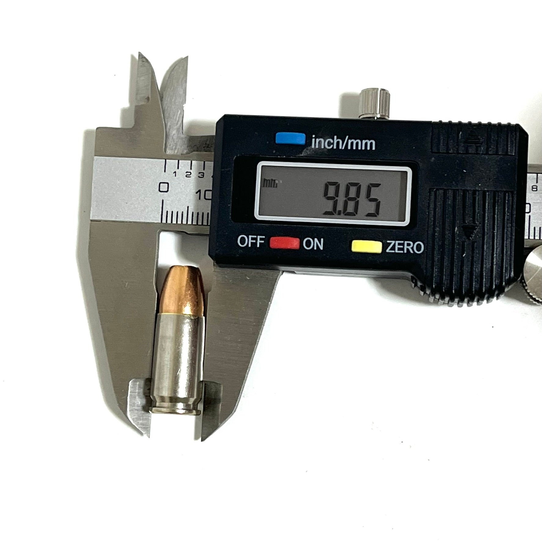 Digital caliper measuring the bullet diameter of an inert 9MM Luger JHP dummy round at 3.87mm. Nickel-plated once-fired brass casing. Precise measurement reference for cosplay and ammo art projects.

