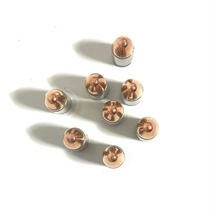 Eight polished 9mm nickel dummy rounds with seated bullets standing upright on a white surface.