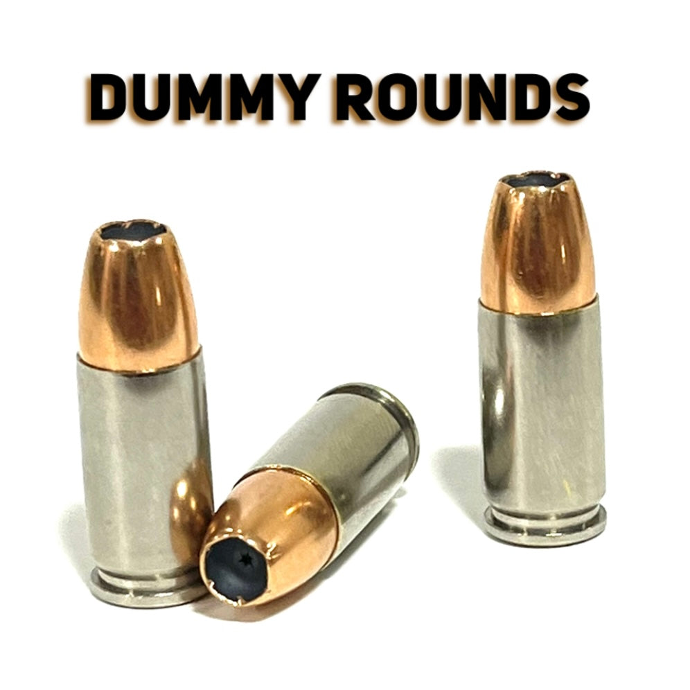 Inert 9MM Luger nickel-plated dummy rounds — two upright, one horizontal — showing JHP jacketed hollow point bullet profile and spent primer. Not live ammunition.
