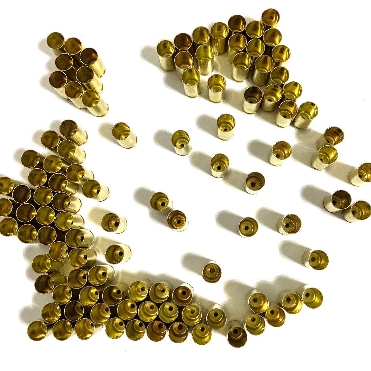 Scattered pile of polished 9mm brass shells showing open mouths and spent primer dimples.
