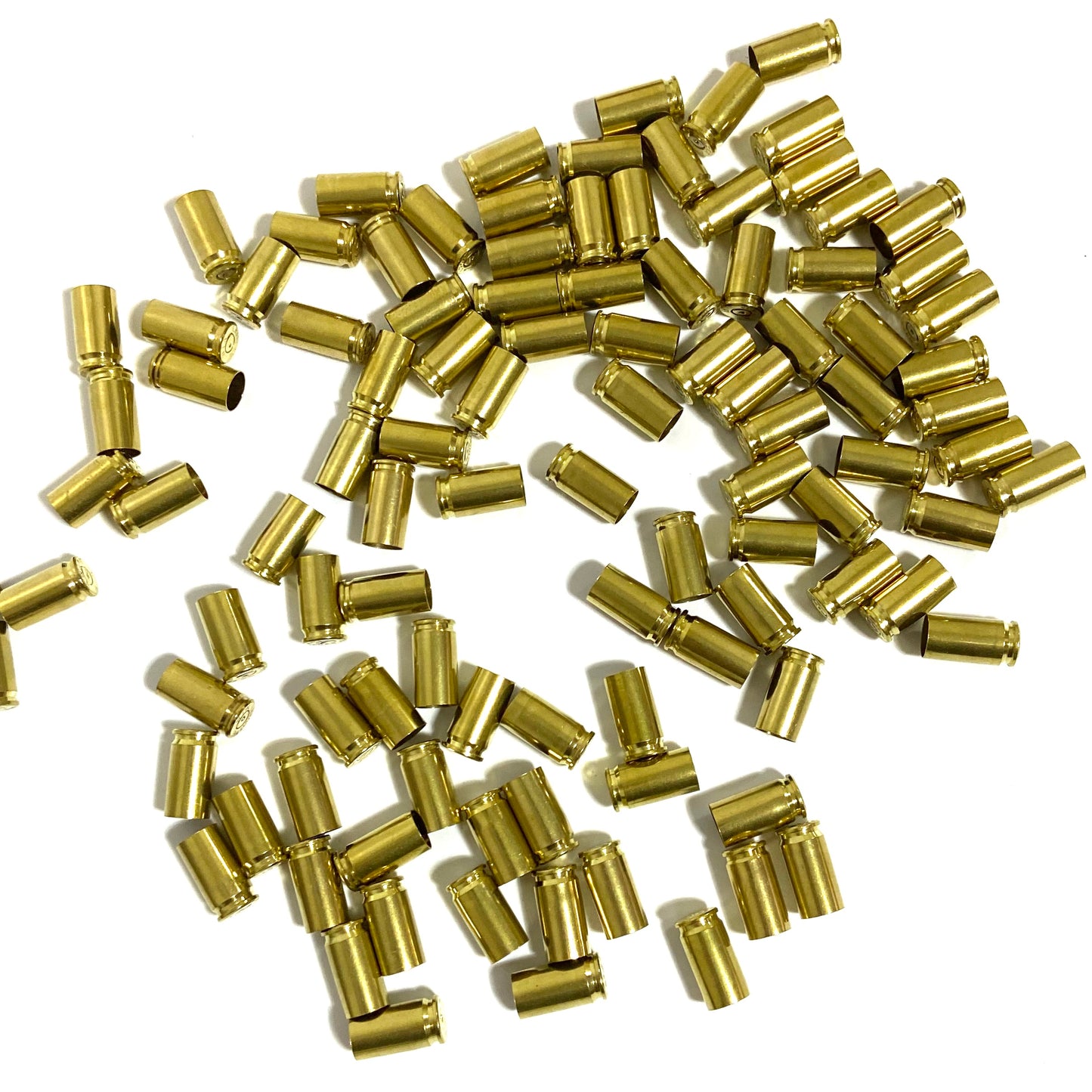 Scattered pile of polished 9mm brass shells showing open mouths and spent primer dimples.
