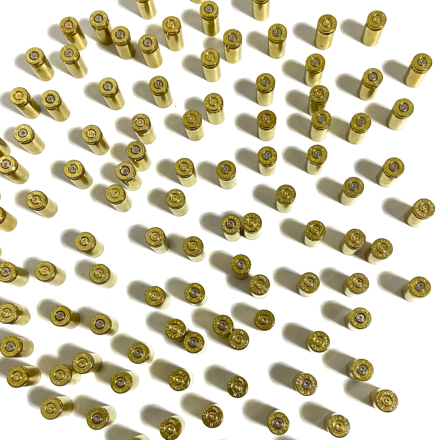 Orderly grid of polished 9mm brass shells showing headstamps and spent primer dimples.
