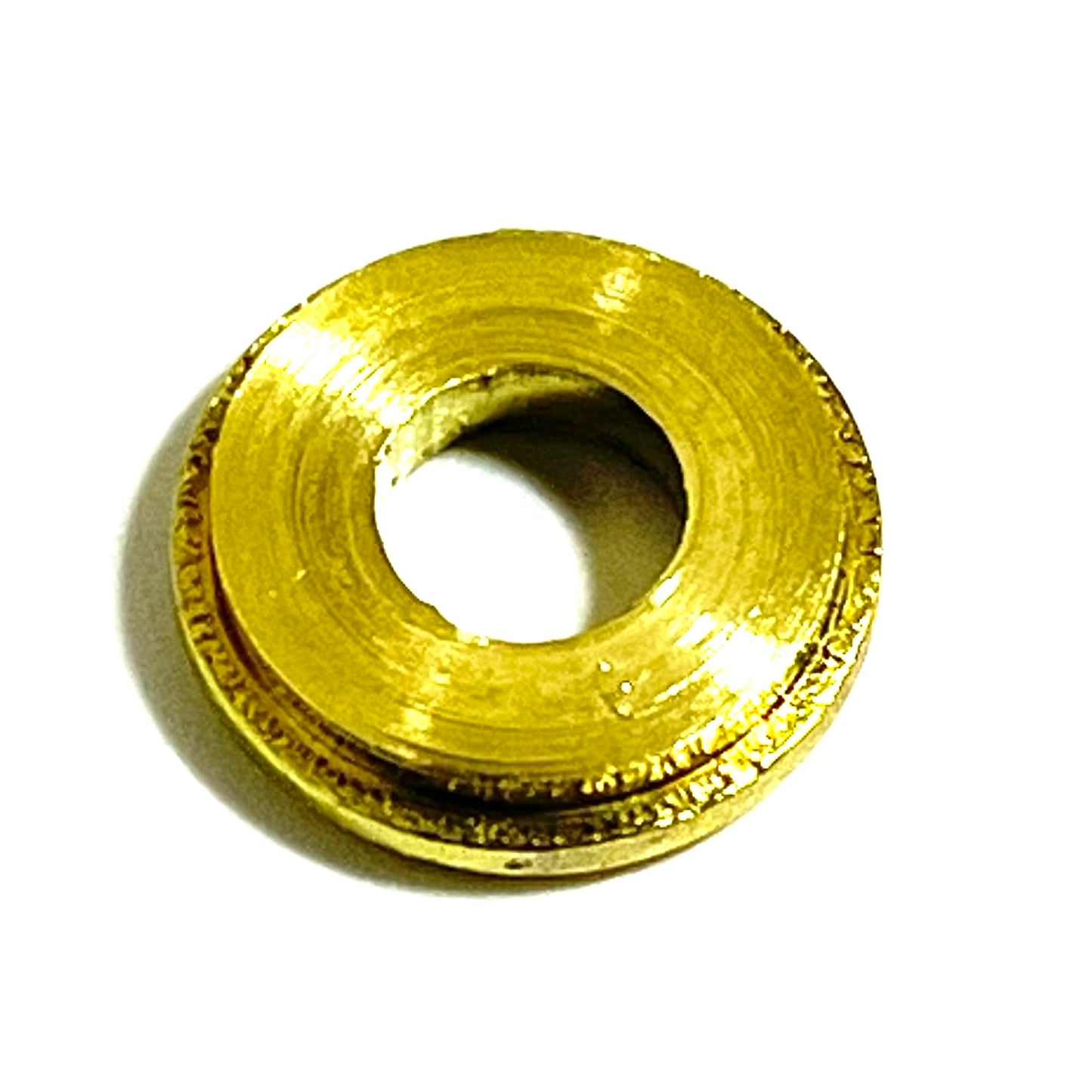 A single brass bullet slice with primer removed shown from its smooth polished side, with the case rim visible along the edge.