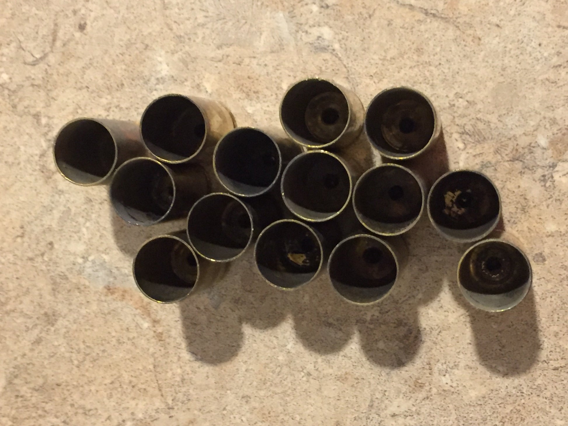 Overhead view of gold 9mm brass casings viewed from the open mouth end, showing hollow interiors