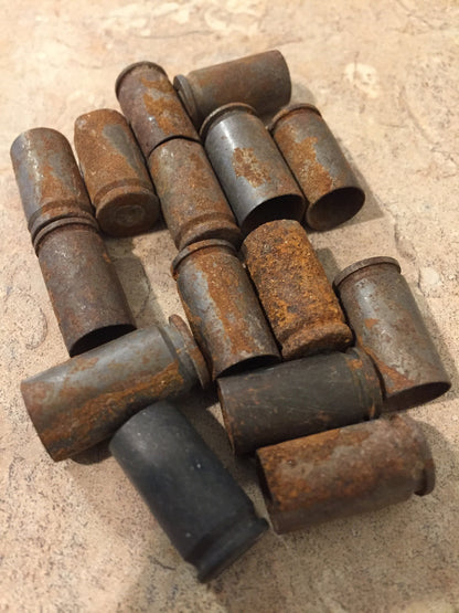 Cluster of rusted 9mm shell casings lying on their sides on tile, orange rust patches over gray brass