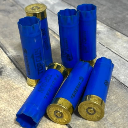 A collection of once fired 12ga Federal blue empty shells lying on a wooden surface.