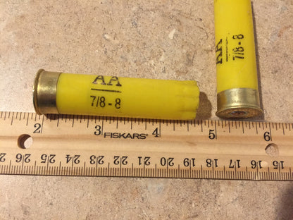 A single empty yellow hull marked 'AA 7/8-8' lies beside a ruler, measuring approximately 2.75 inches.