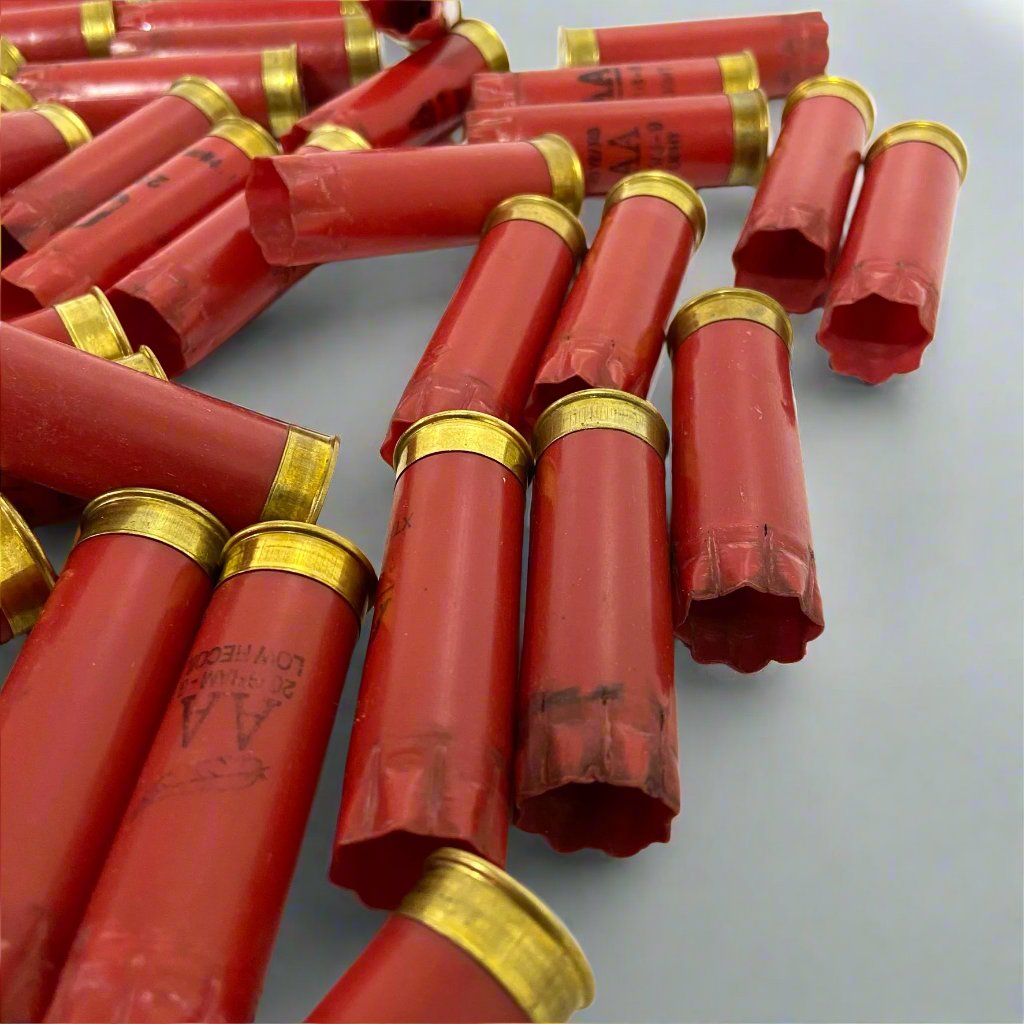AA Red shotgun shell hulls scattered loosely at angles on a gray surface, brass bases visible