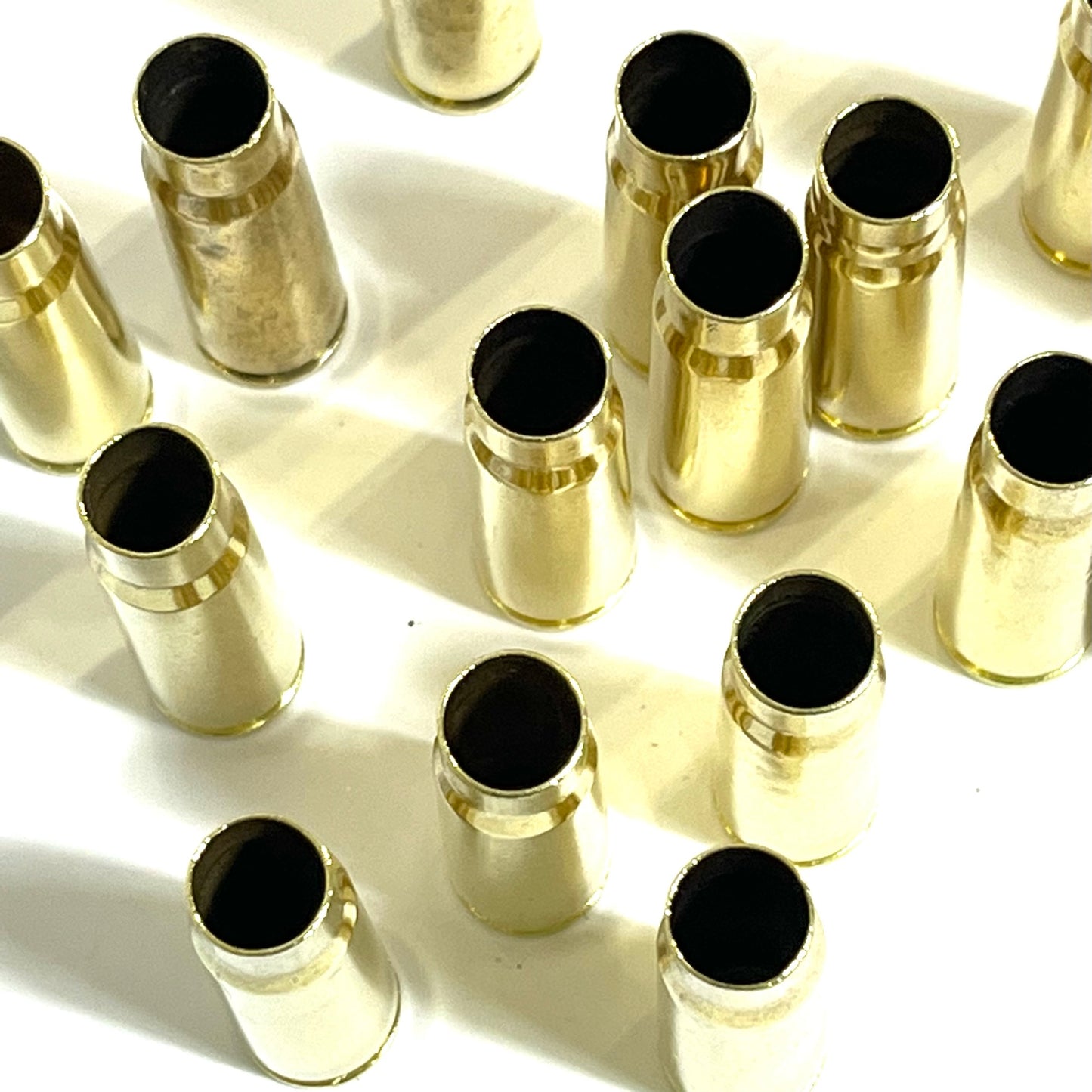 Many empty brass casings viewed from above, open mouths facing up in a scattered grid pattern.
