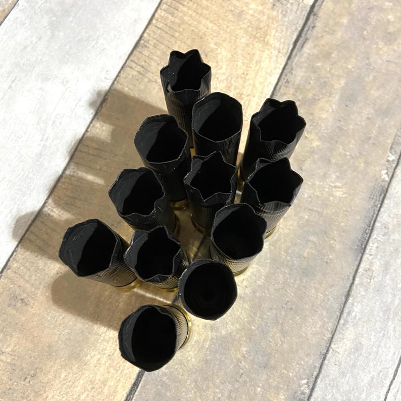 12 black empty shotgun shells standing upright with star crimp tops and brass bases
