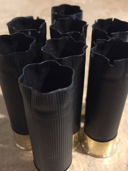 A cluster of black shotshells viewed from above showing open, crimped tops and hollow interiors
