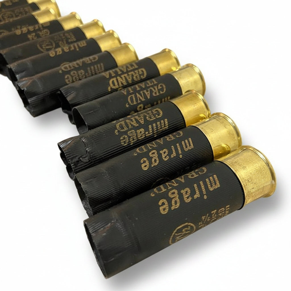 Black Mirage shotgun cartridges lined up diagonally on a tabletop, brass bases facing forward.
