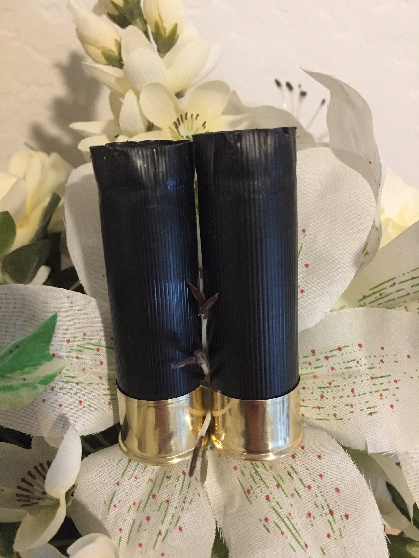 Two once-fired black shotgun shells tied together as a boutonniere with white flowers