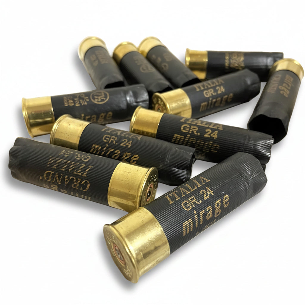 Several black Italia and Mirage shotgun shells scattered and crossed on a wooden surface, showing brass bases.