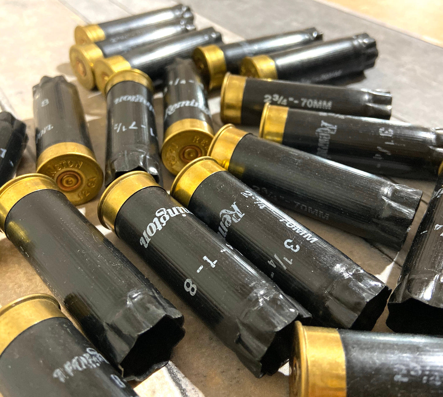 Black 12 gauge empty shotgun shells with gold Remington bases scattered on a tile countertop