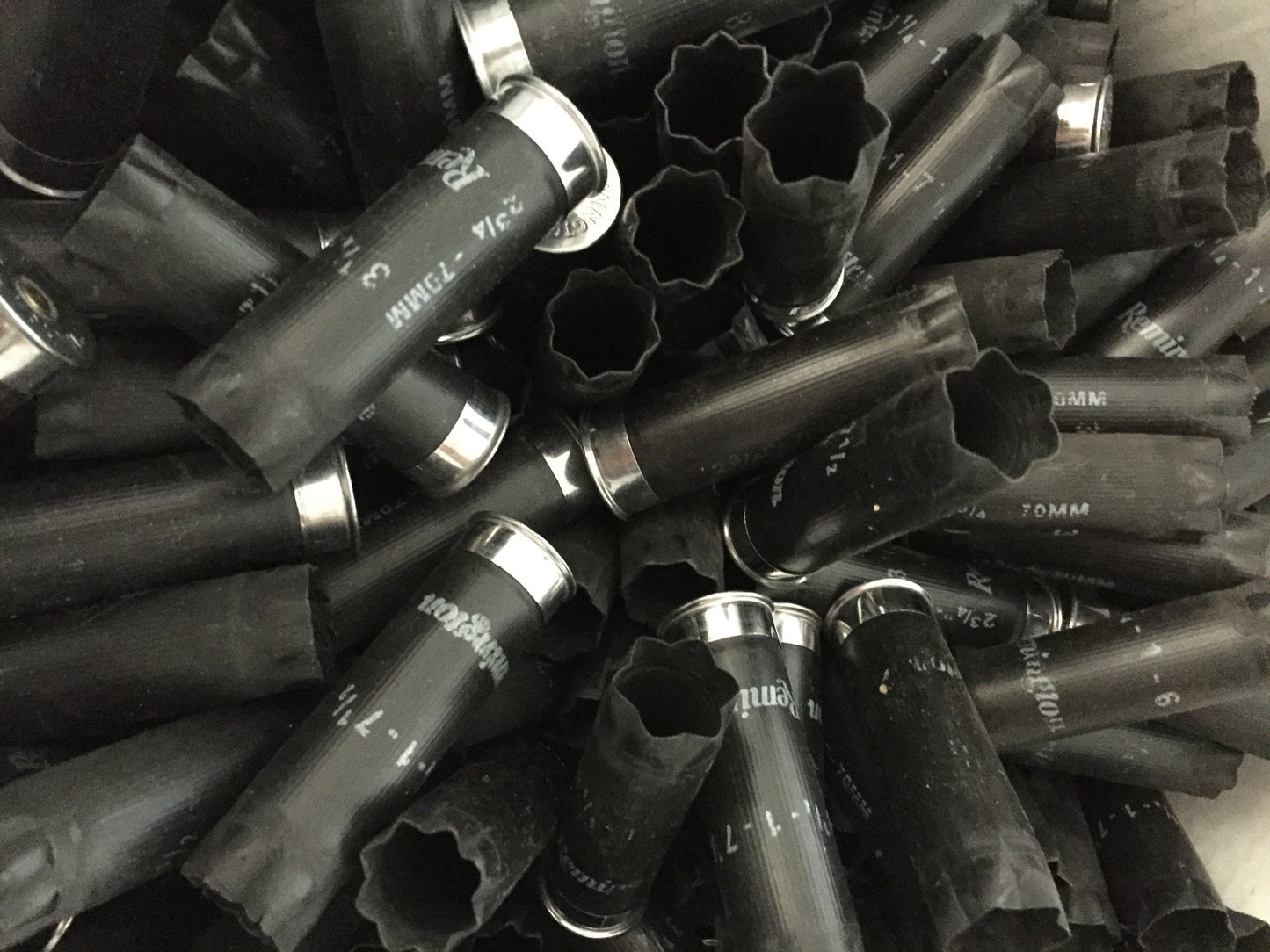 Close-up pile of black Remington 12 gauge empty shotshells showing open crimped ends and silver metal bases.