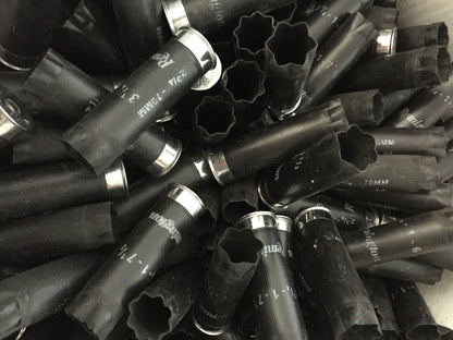 Close-up pile of black Remington 12 gauge empty shotshells showing open crimped ends and silver metal bases.