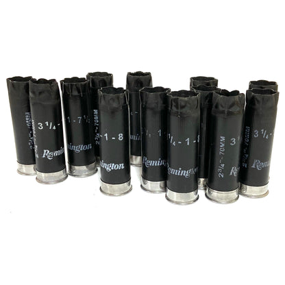 Group of black Remington 12 gauge spent shotgun shells standing upright on a white background.
