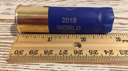 Blue Rio 2018 World Cup shotgun shell with a gold brass base measured against a ruler, showing a length of about 2.75 inches