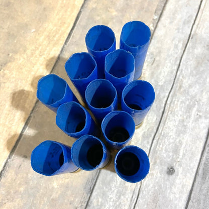 10 blue Fiocchi 16 gauge shotgun shells viewed from above showing open mouths on a wood surface