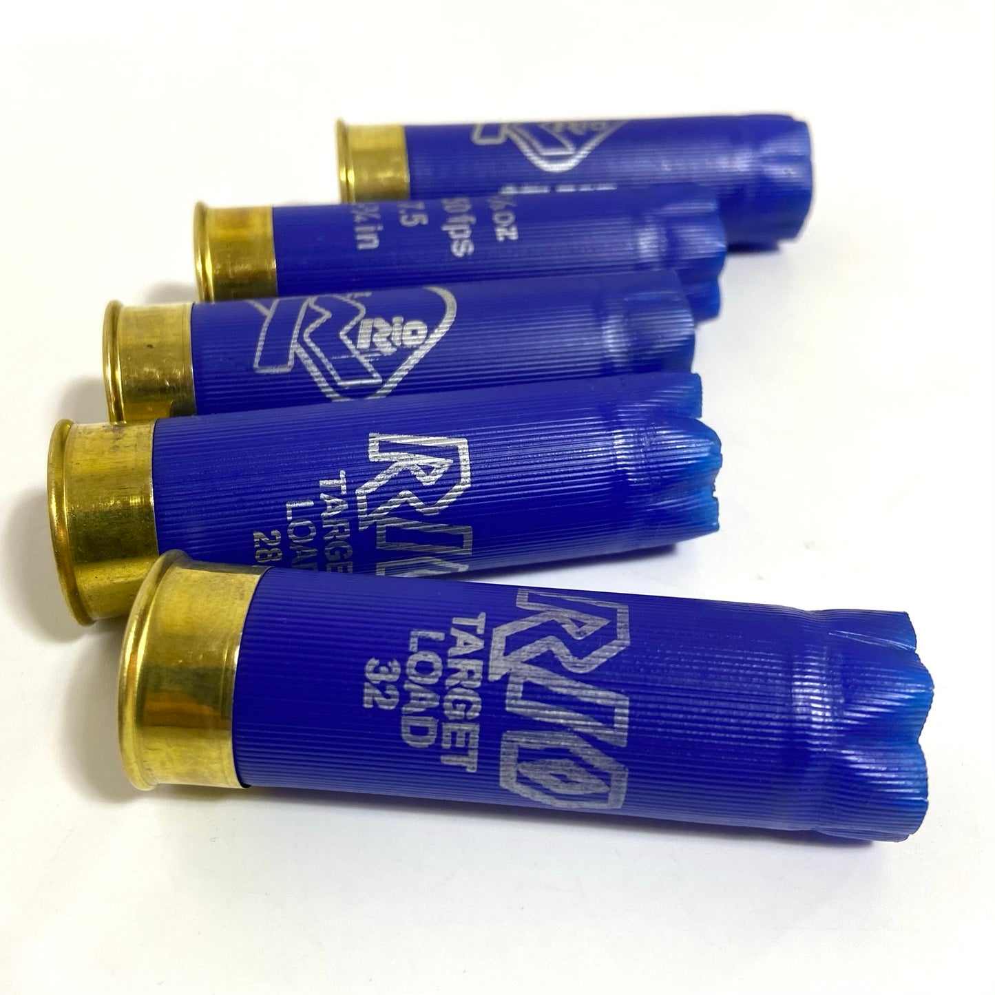 Five blue Rio 12 gauge empty casings lying horizontally side by side on a plain white surface.