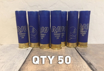 Seven blue Rio 12 gauge shotgun hulls standing upright in a row on a wood surface with white QTY 50 text overlay.