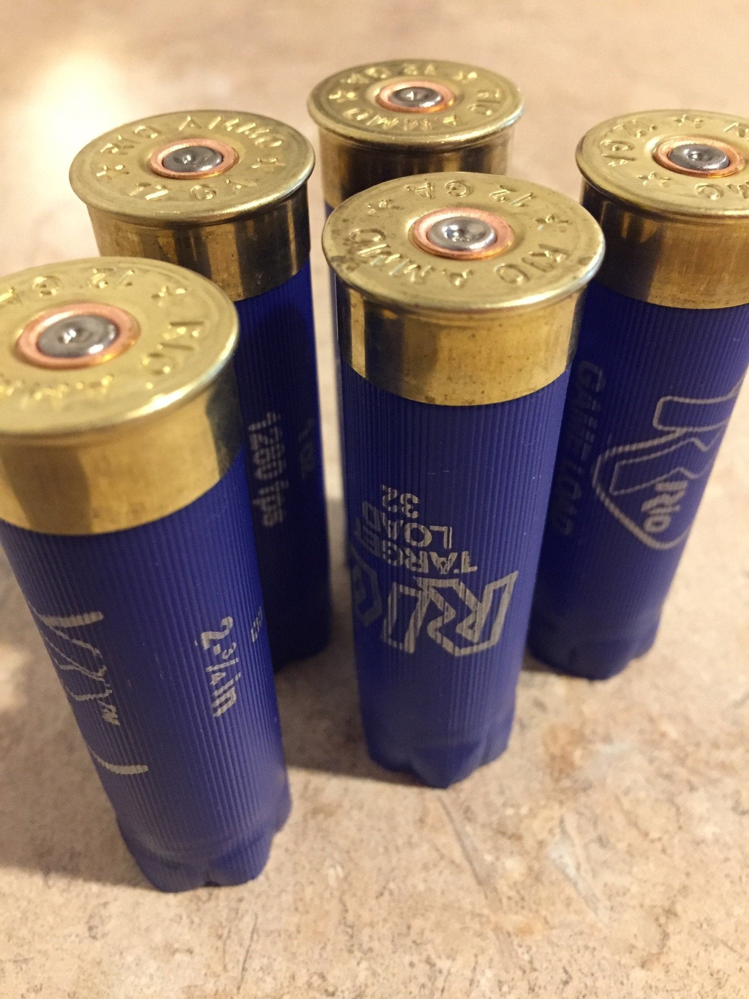 Close up view of blue Rio 12 gauge shotgun shells standing upright showing stamped brass bases and spent primers.