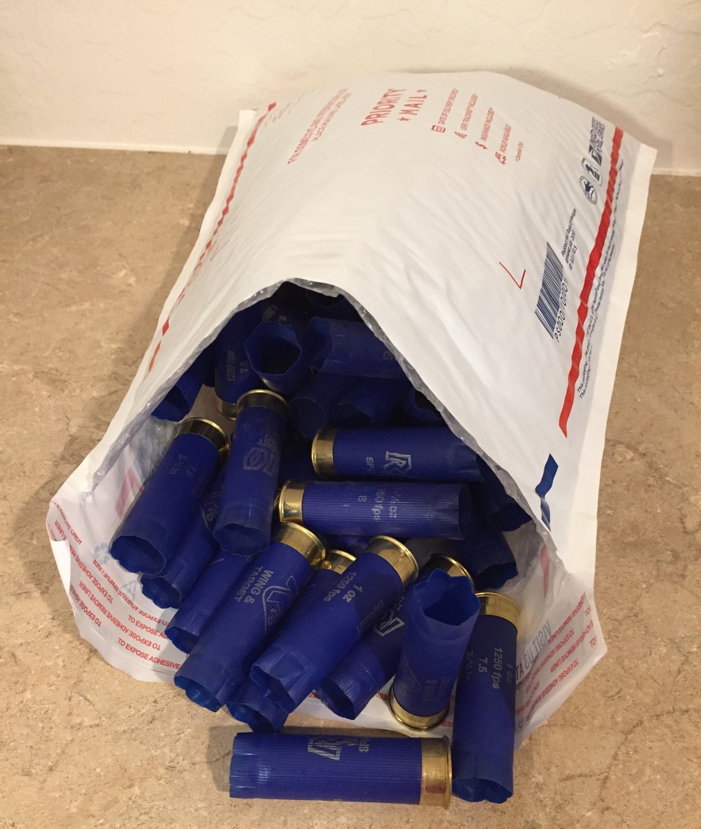 Bulk collection of blue Rio 12 gauge shotgun shells packed inside a padded USPS Priority Mail envelope.