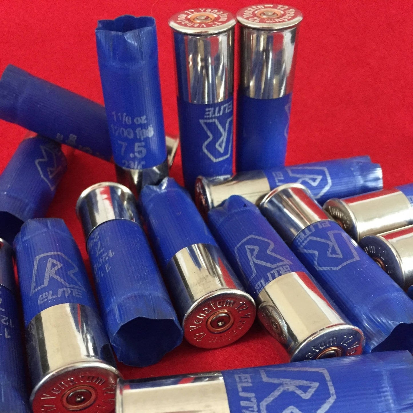 Blue empty shotgun shells with high brass silver rims scattered on a bright red surface.
