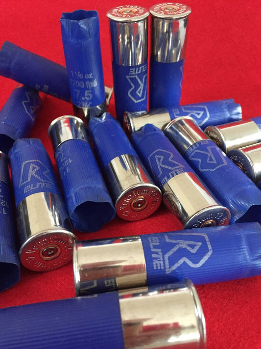 Blue empty shotgun shells with high brass silver rims scattered on a bright red surface.
