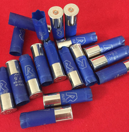 A pile of blue inert shotgun shells with shiny metal casings scattered randomly on a bright red surface.