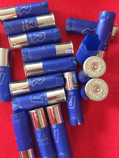 Close-up of empty blue shotshells clustered together, displaying their round metal ends on a red surface.