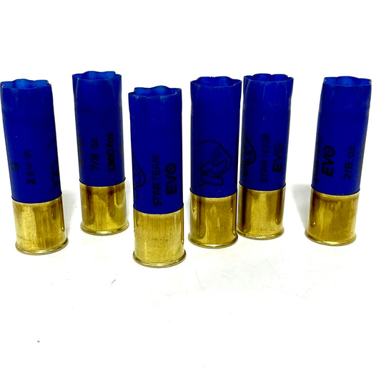 Six empty blue 12 gauge shotgun shells standing in a row with high brass bases for wedding-boutonnieres.
