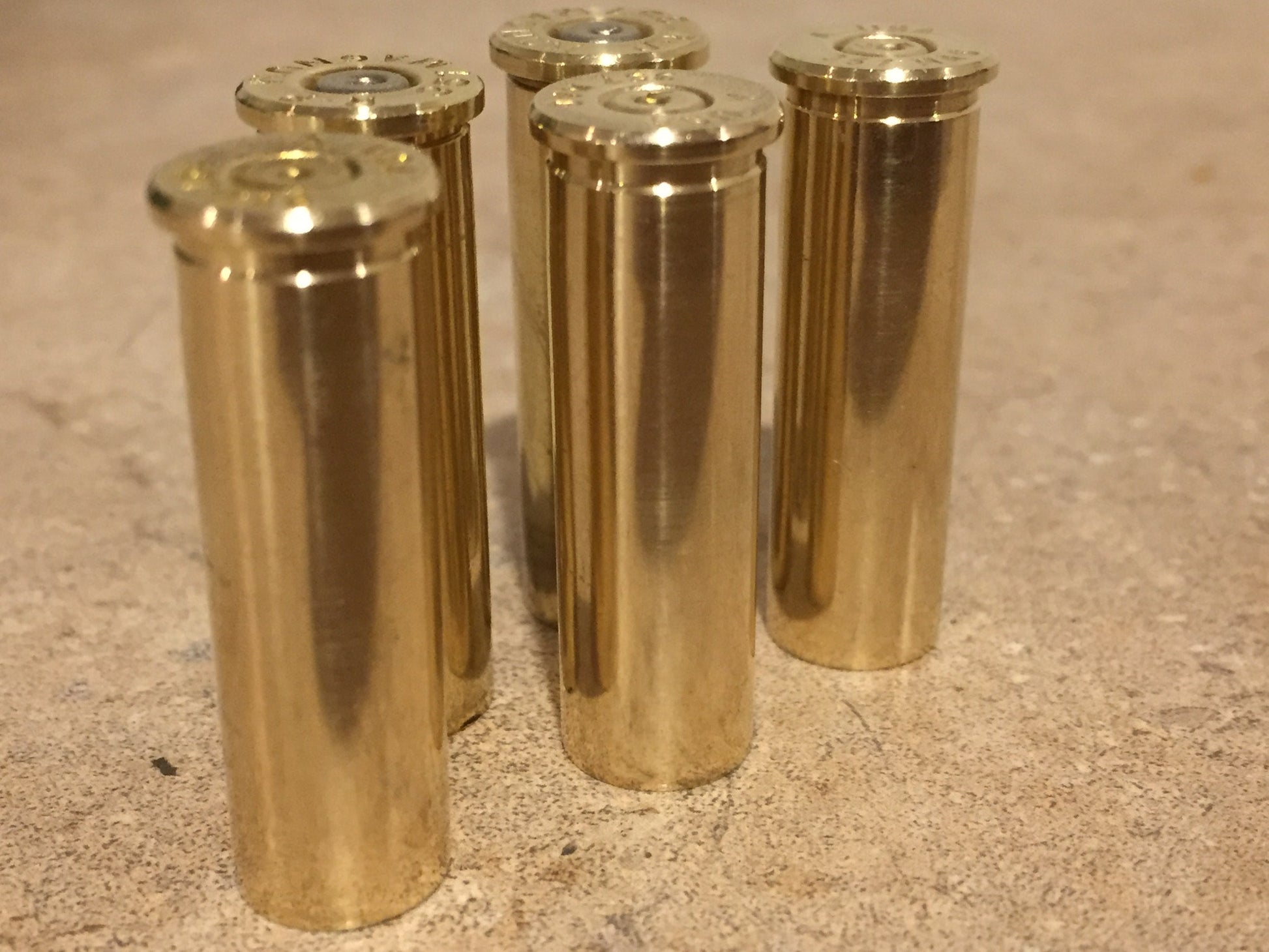 Five polished brass 357 Magnum cases standing upright on a tan countertop, showing base rims and spent primers.