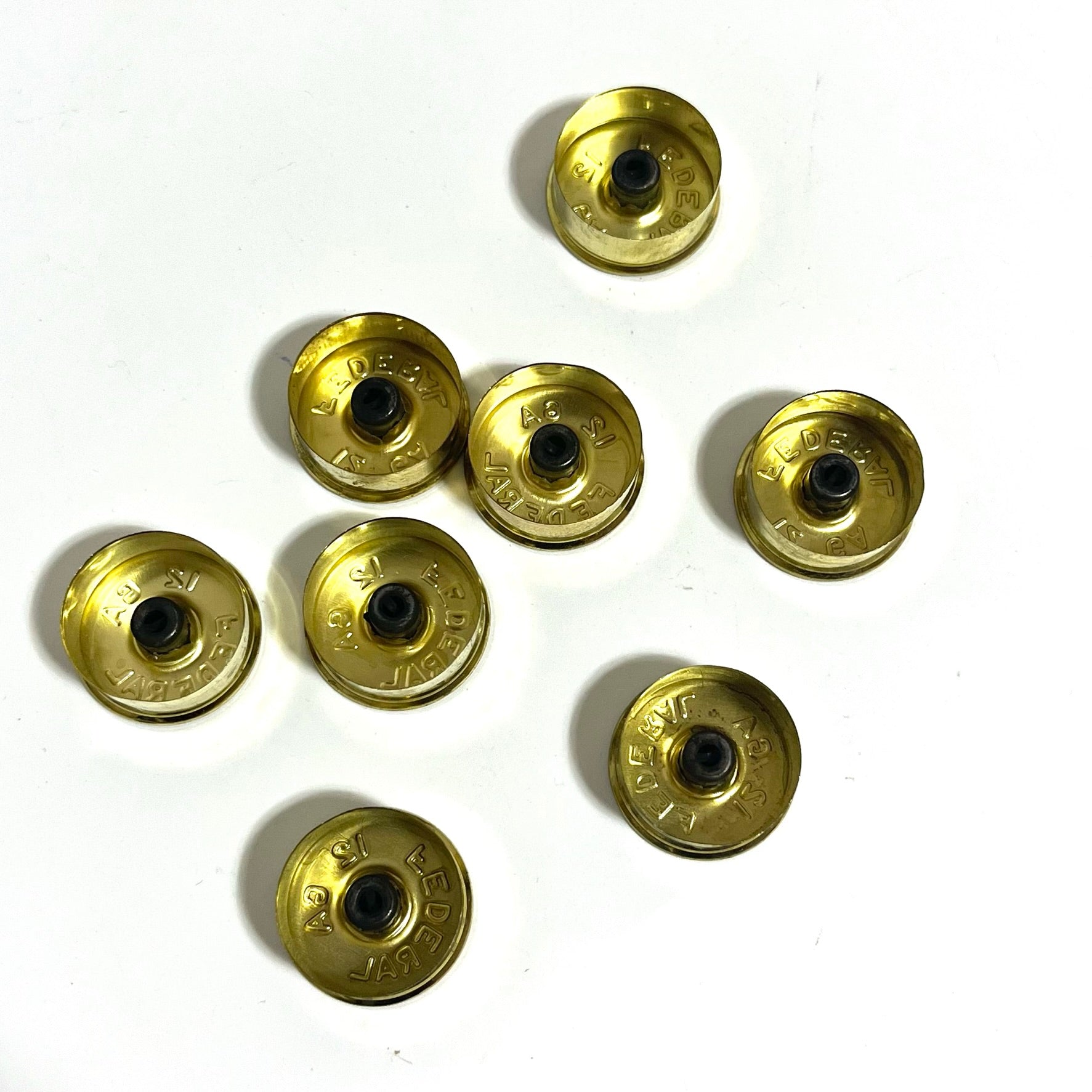8 gold brass 12 gauge Federal shotgun shell headstamp bottoms scattered on a white background