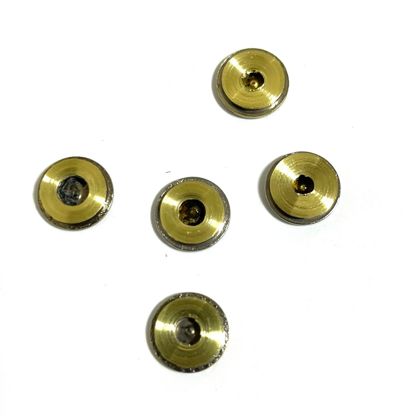 Five brass bullet slices bottom view  arranged in a cross design pattern on a solid white background.
