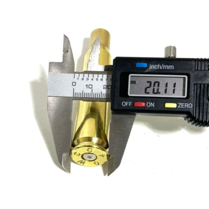 Empty brass cartridge base measured with a digital caliper reading 20.11 mm, on white background.