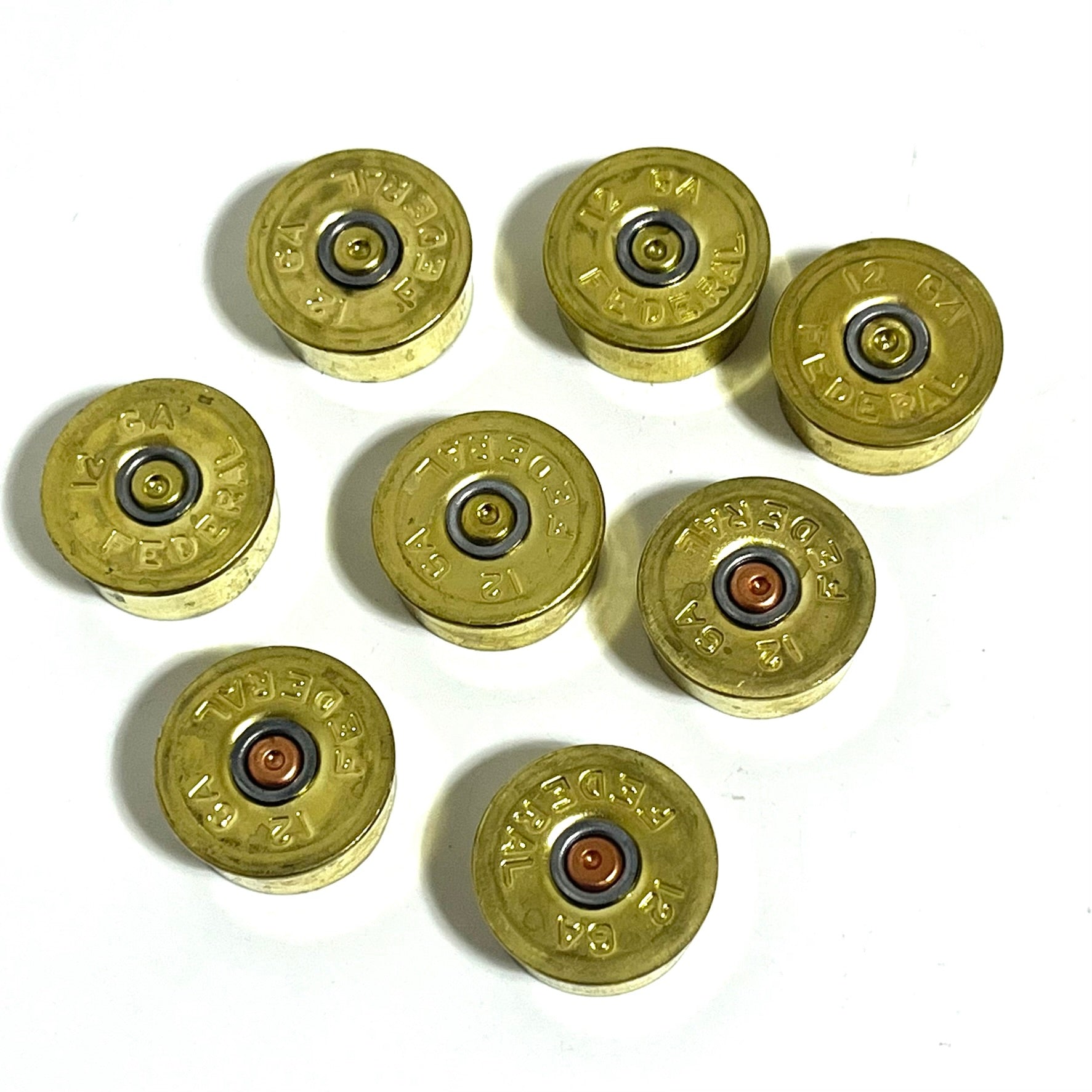 8 gold brass 12 gauge Federal shotgun shell headstamp bottoms arranged in a cluster on a white background