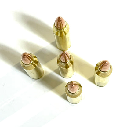 Five inert brass 5.56 NATO rounds standing vertically on a white background, highlighting the copper bullet tips from above.