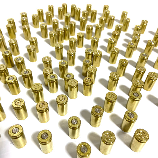 Once-fired brass 9mm casings standing upright in neat rows, with primers visible at their bases.