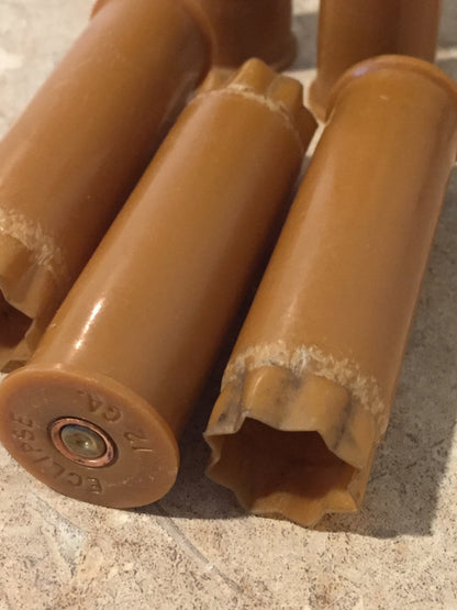 Closeup of brown tan 12 gauge shotgun shells showing a brass base stamped ‘Eclipse 12 GA’ and worn star-crimped tops