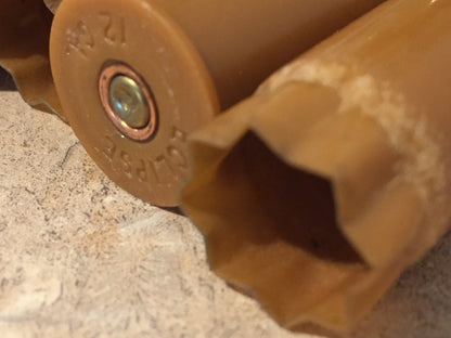 Closeup of a brown tan 12 gauge shotgun shell base stamped ‘Eclipse 12 GA’ beside an open star-crimped mouth