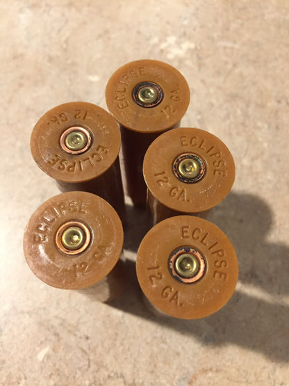 Five brown tan ‘Eclipse’ 12 gauge shotgun shell bases viewed from above, showing brass primers