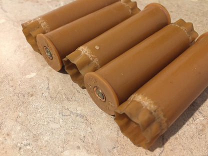 Row of brown tan 12 gauge shotgun shells lying diagonally, showing brass bases and worn star-crimped tops
